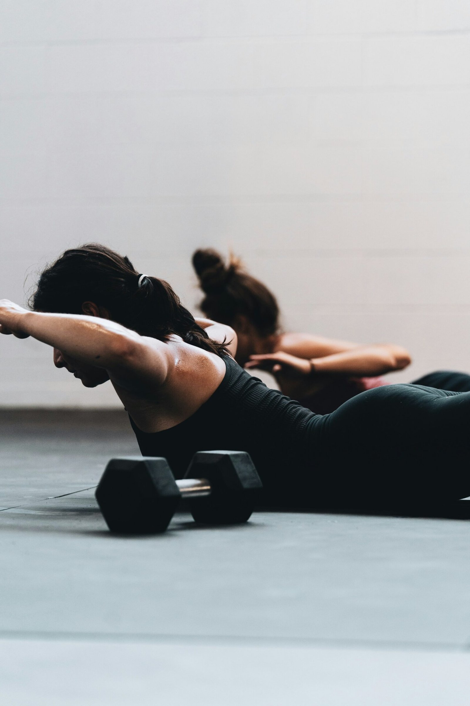 Two females working out with a weight on the floor beside them